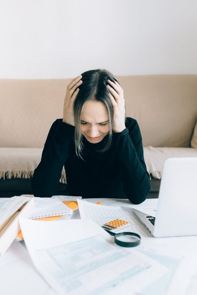 ๐ Title: The Midnight Money Spiral: How Budgeting Brought Me Peace (and Sleep!) 2 A woman appears stressed and overwhelmed with paperwork at her home desk.