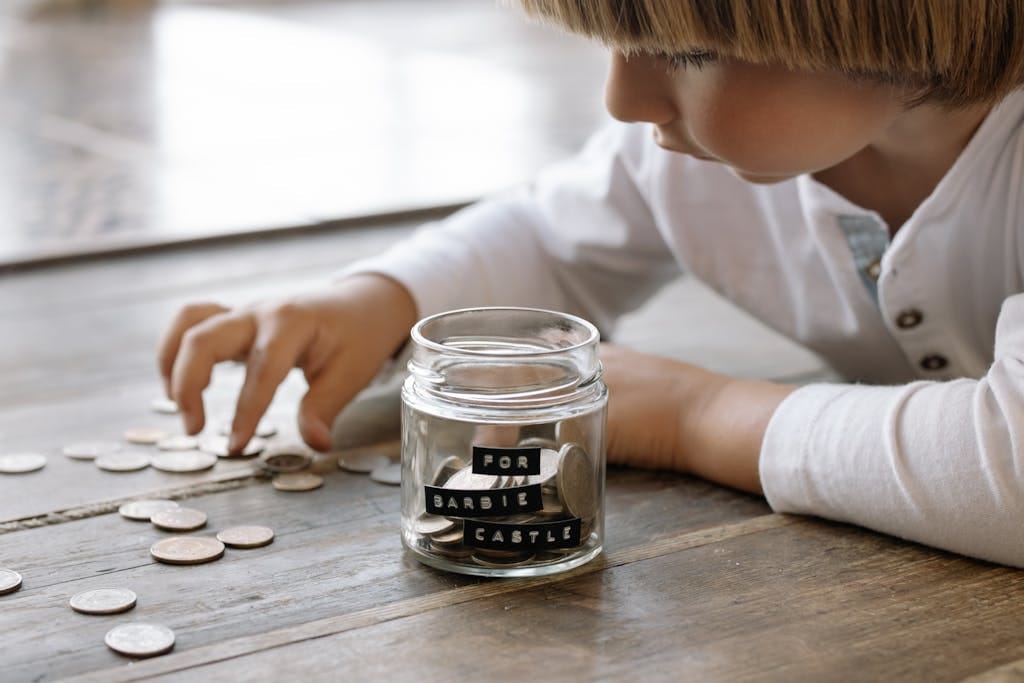 How Small Investments Can Turn Your Pocket Money into a Fortune 💷✨ 2 A young child collects coins in a jar labeled 'For Barbie Castle', symbolizing saving and dreams.