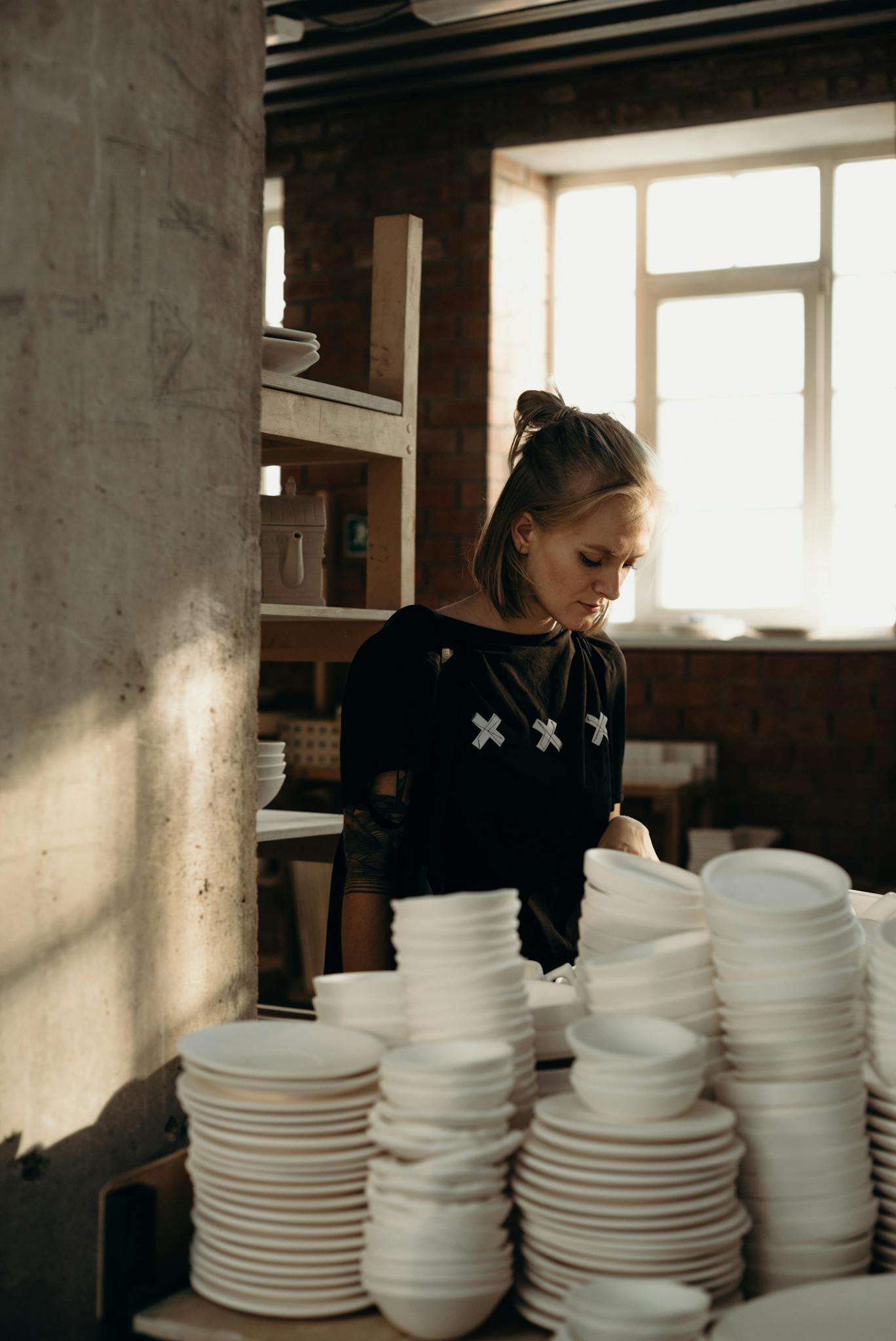 About 3 focused artisan in ceramics studio among handcrafted