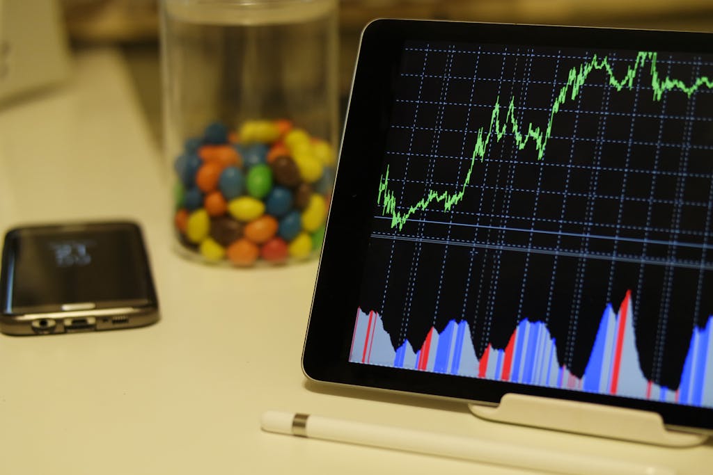 Stock Market? I Thought It Was Just for Rich People with Yacht Shoes 🚤💼 2 Tablet display of stock market data with smartphone and colorful candies on desk.