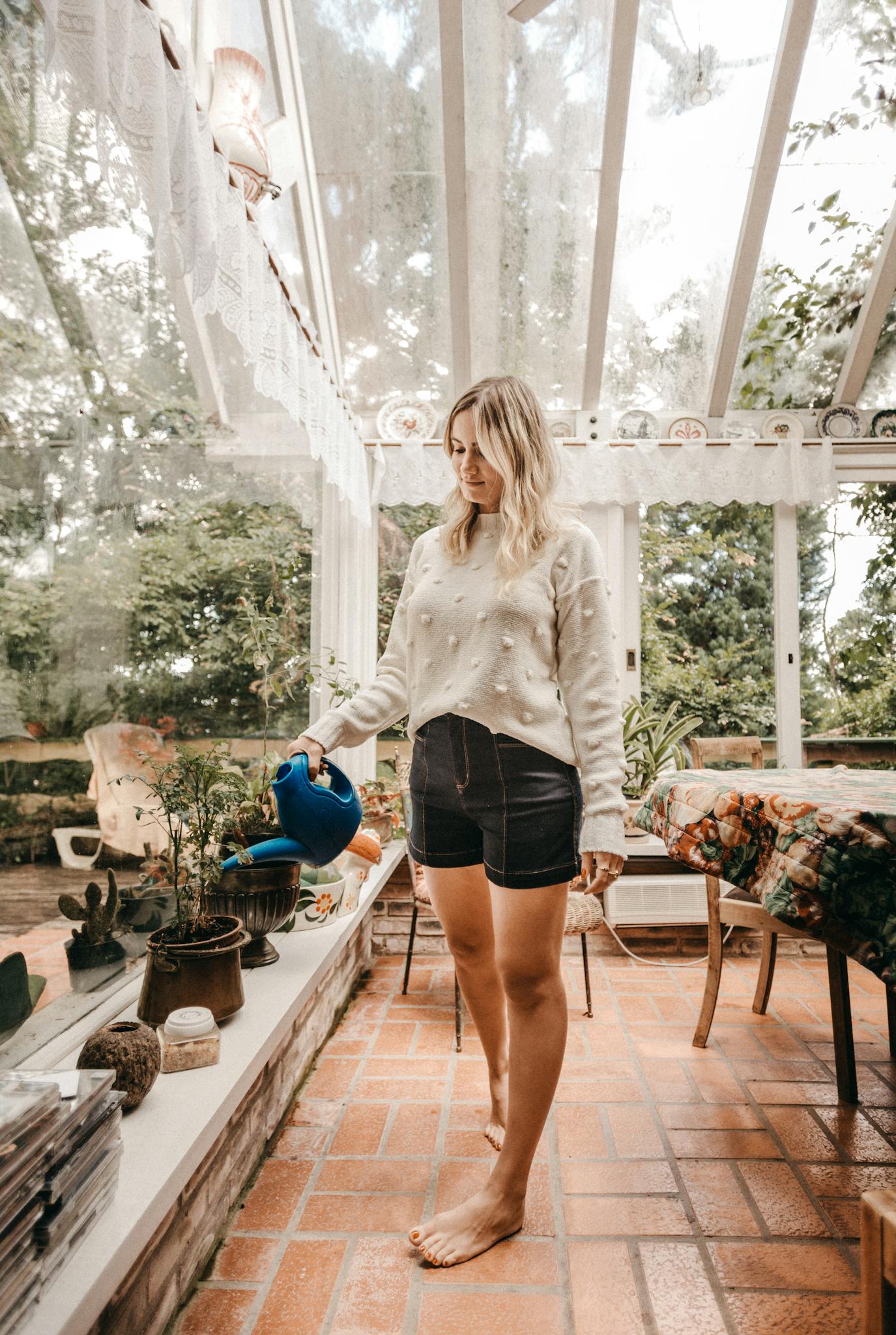 About 2 woman in a stylish outfit watering houseplants